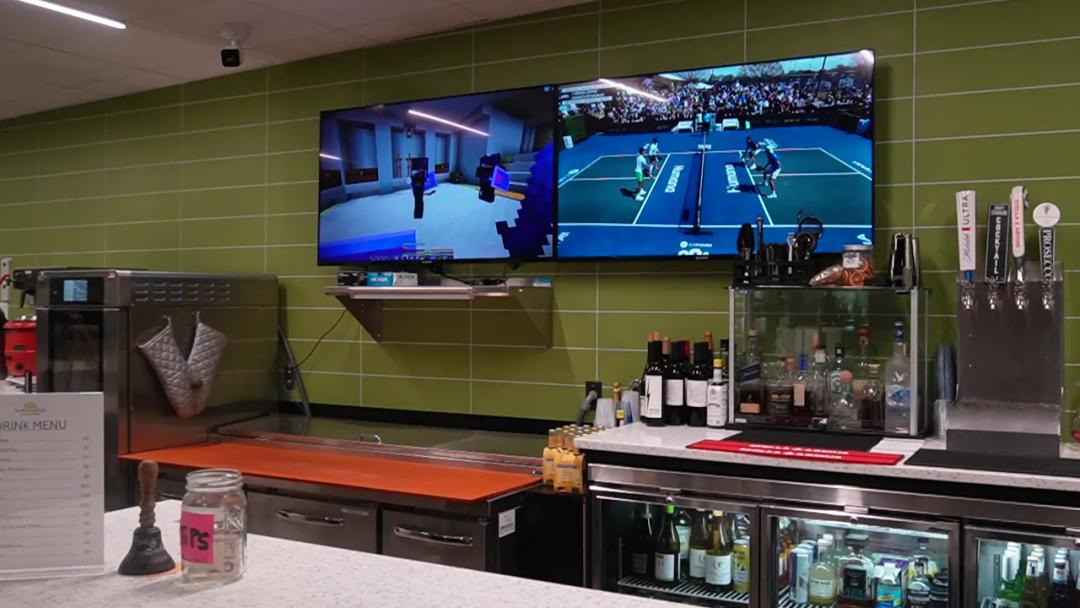 TV screens above the bar showing live pickleball